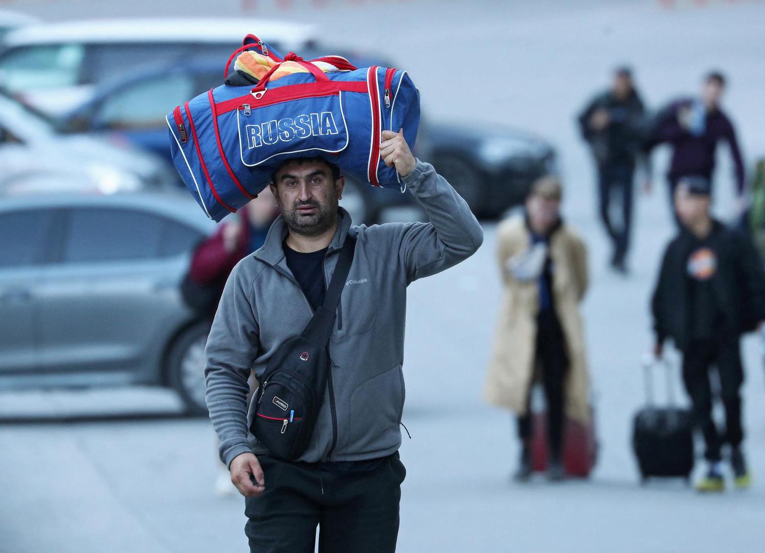 A man carries a bag on his head as travellers from Russia cross the border to Georgia at the Zemo Larsi/Verkhny Lars station, Georgia September 26, 2022. REUTERS/Irakli Gedenidze Photo: IRAKLI GEDENIDZE/REUTERS