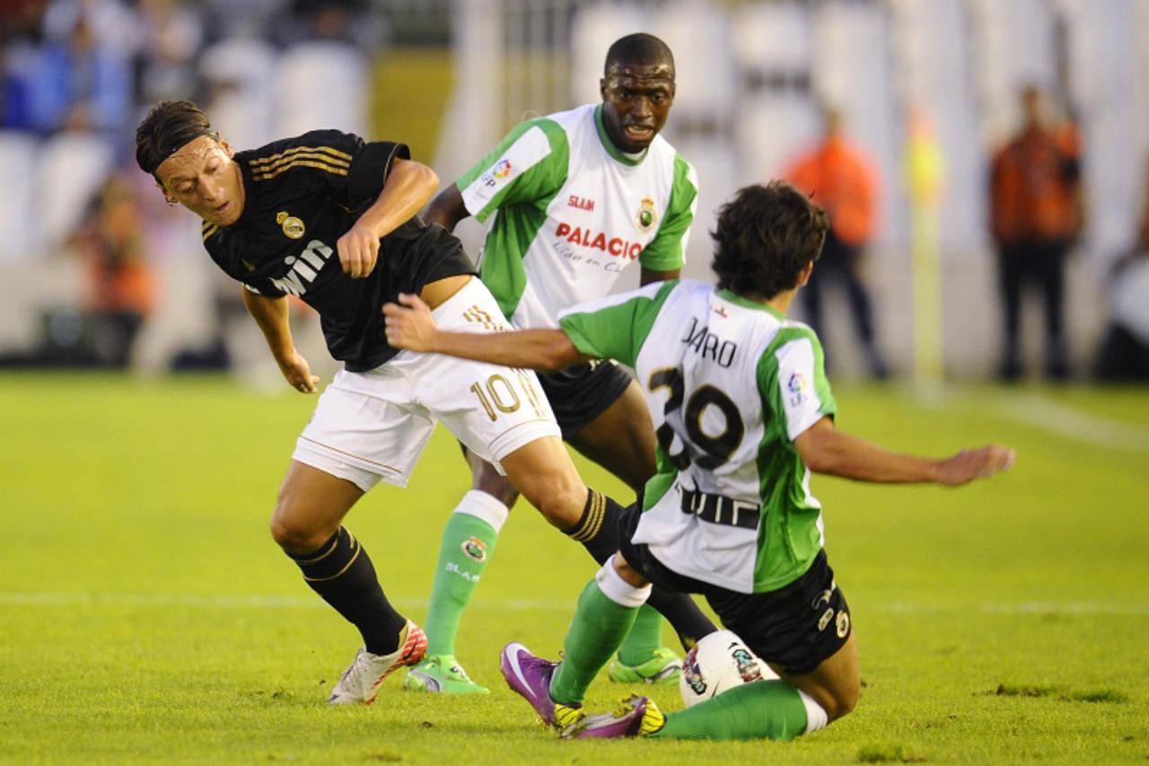 'Racing Santander\'s Jaro (R) and Papakouli Diop (C) fights for the ball with Real Madrid\'s Mesut Ozil during their Spanish first division soccer match at El Sardinero stadium in Santander September 