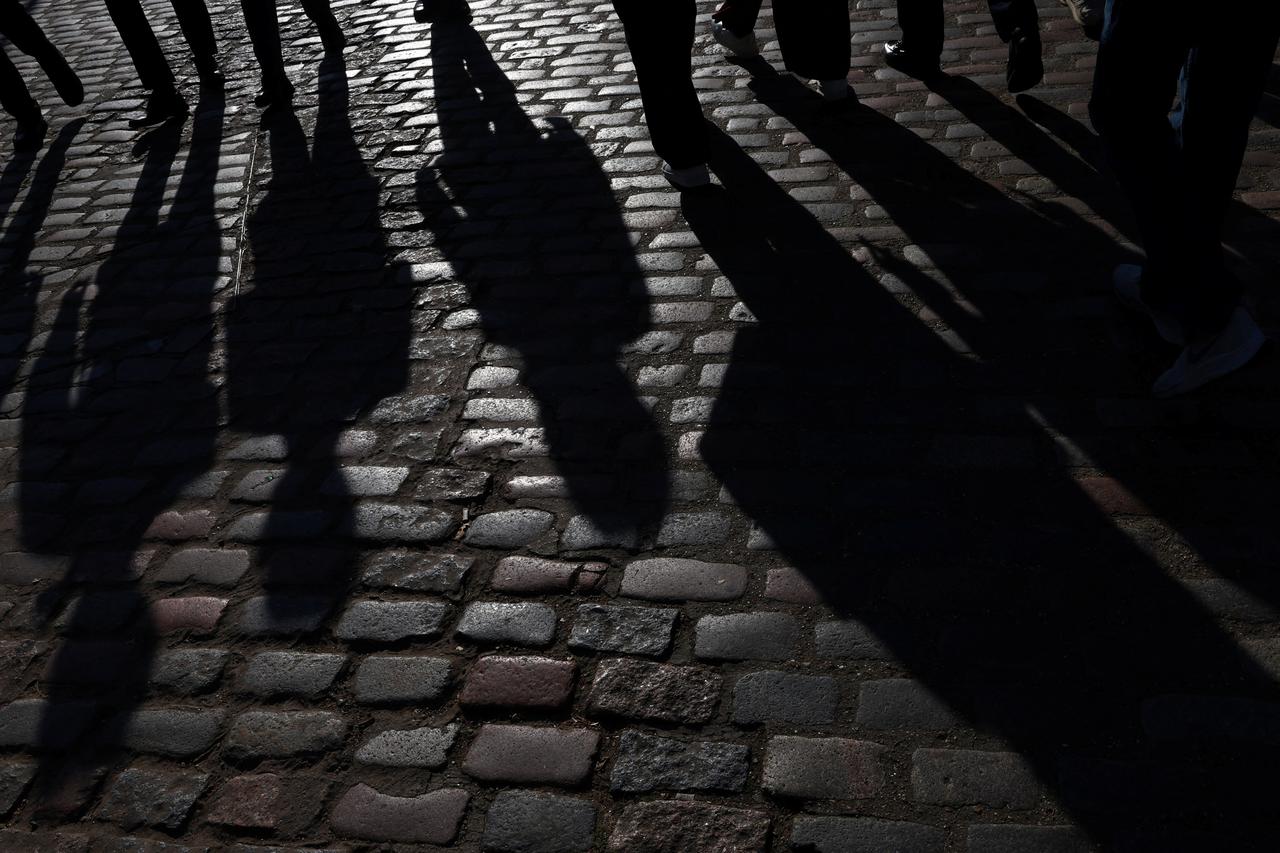 People walk in late afternoon sunlight in London