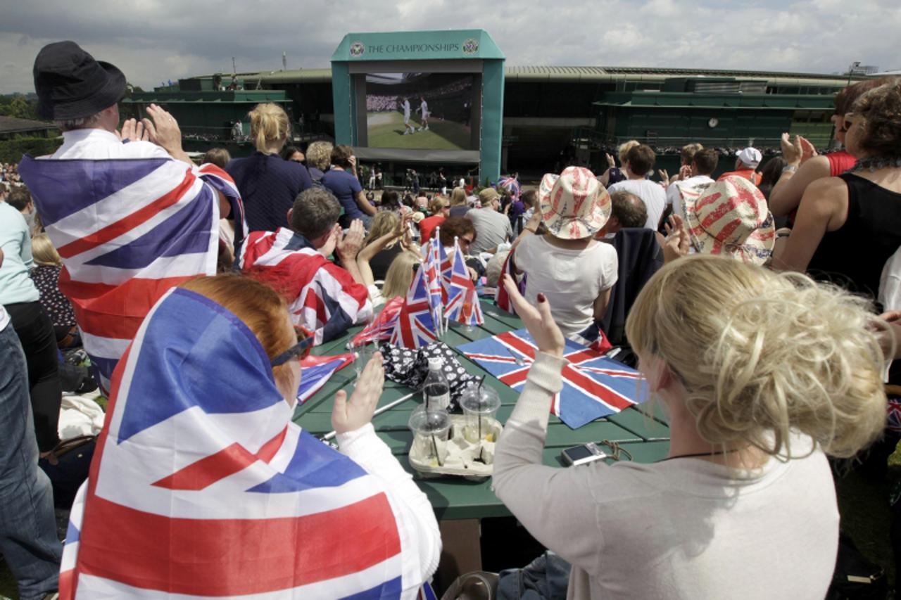 'Spectators sit on Murray Mound (also known as Henman Hill) as the players walk onto court for the men\'s singles final tennis match between Roger Federer of Switzerland and Andy Murray of Britain at 