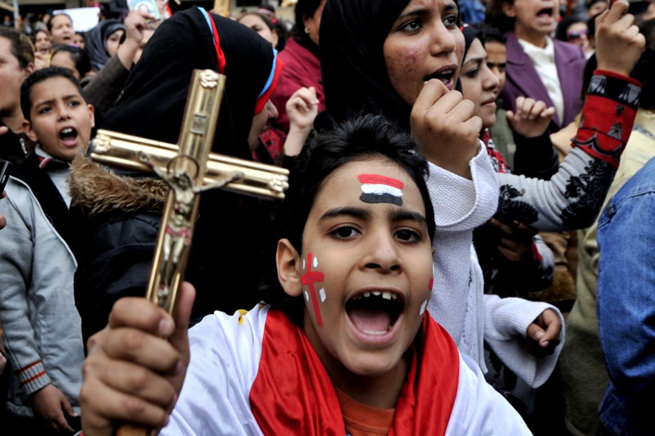 'An Egyptian Coptic Christian boy shouts slogans while holding a crucifix during a protest outside the Egyptian state television building in Cairo on March 10, 2011. Sectarian clashes killed at least 