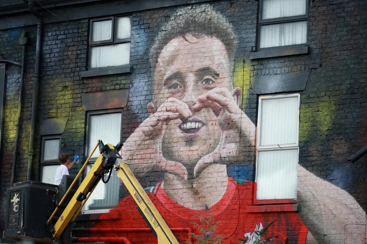 Artist John Culshaw works on a mural of late Liverpool player Diogo Jota on the side of a pub in Liverpool