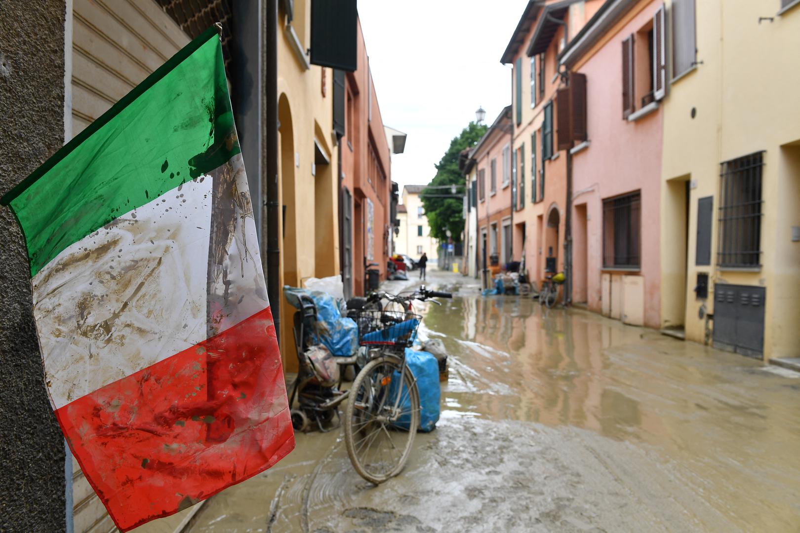 An Italian flag covered in mud flutters on a flooded street, after heavy rains hit Italy's Emilia Romagna region, in Castel Bolognese, Italy, May 18, 2023. REUTERS/Jennifer Lorenzini Photo: JENNIFER LORENZINI/REUTERS