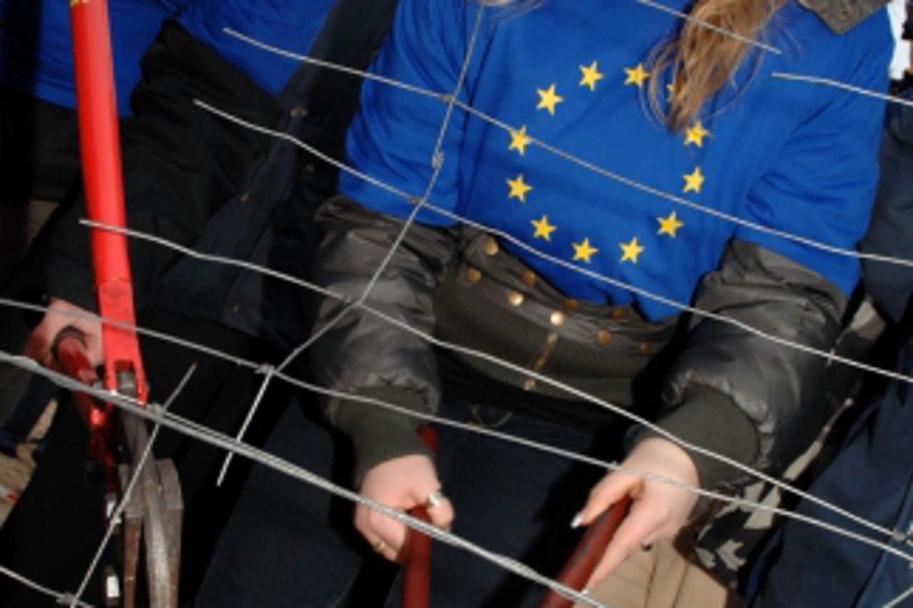 'Polish youth wearing European union t-shirts cut down a wire fence protecting the border between Germany and Poland on the island of Usedom on the Baltic Sea, 21 December 2007. After Poland joined th