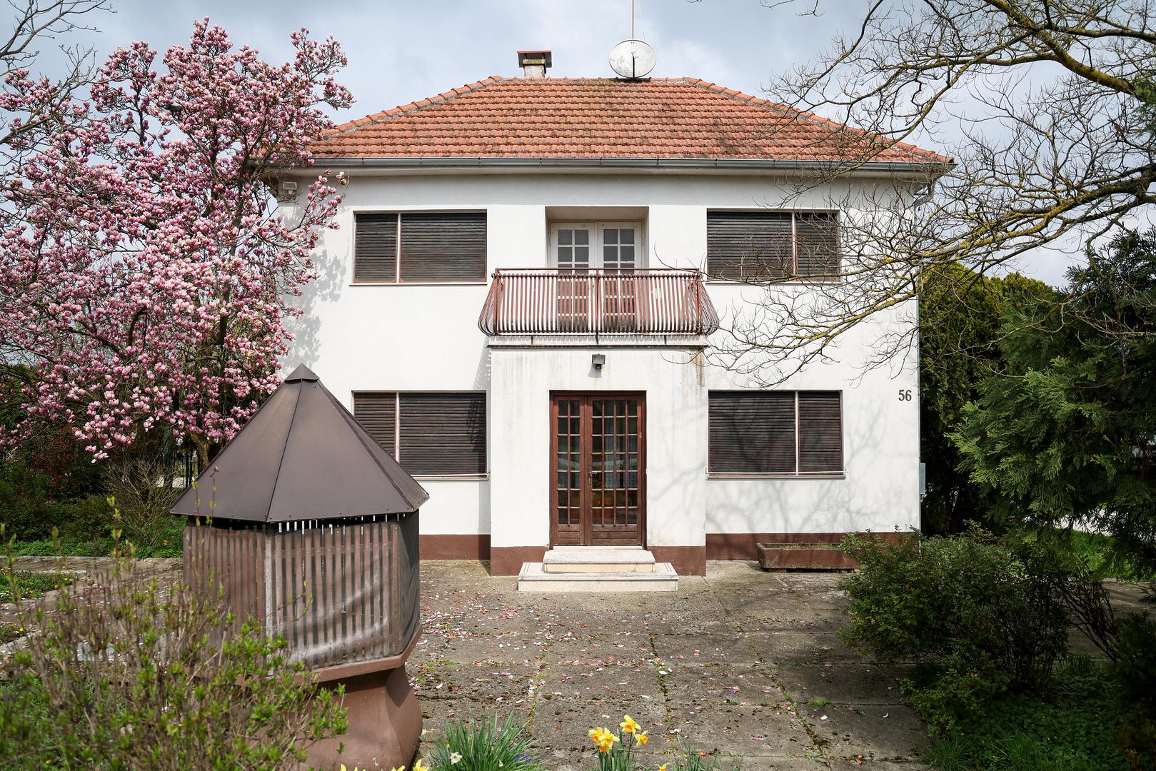 Na tabli ispred kuće piše kako je kuća na prodaju. 