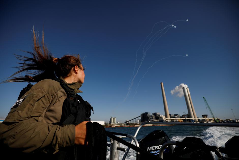 An Israeli soldier looks on as Israel's Iron Dome anti-missile system intercept rockets launched from the Gaza Strip towards Israel, as it seen from a naval boat patrolling the Mediterranean Sea