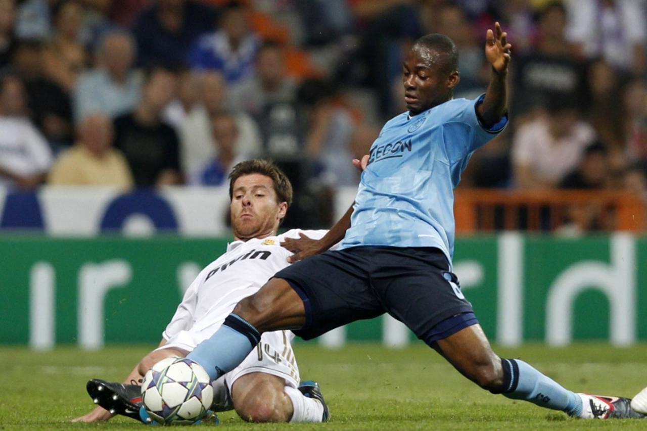 'Real Madrid\'s Xabi Alonso (L) fights for the ball with Ajax Amsterdam\'s Eyong Enoh during their Champions League Group D soccer match at the Santiago Bernabeu stadium in Madrid September 27, 2011. 