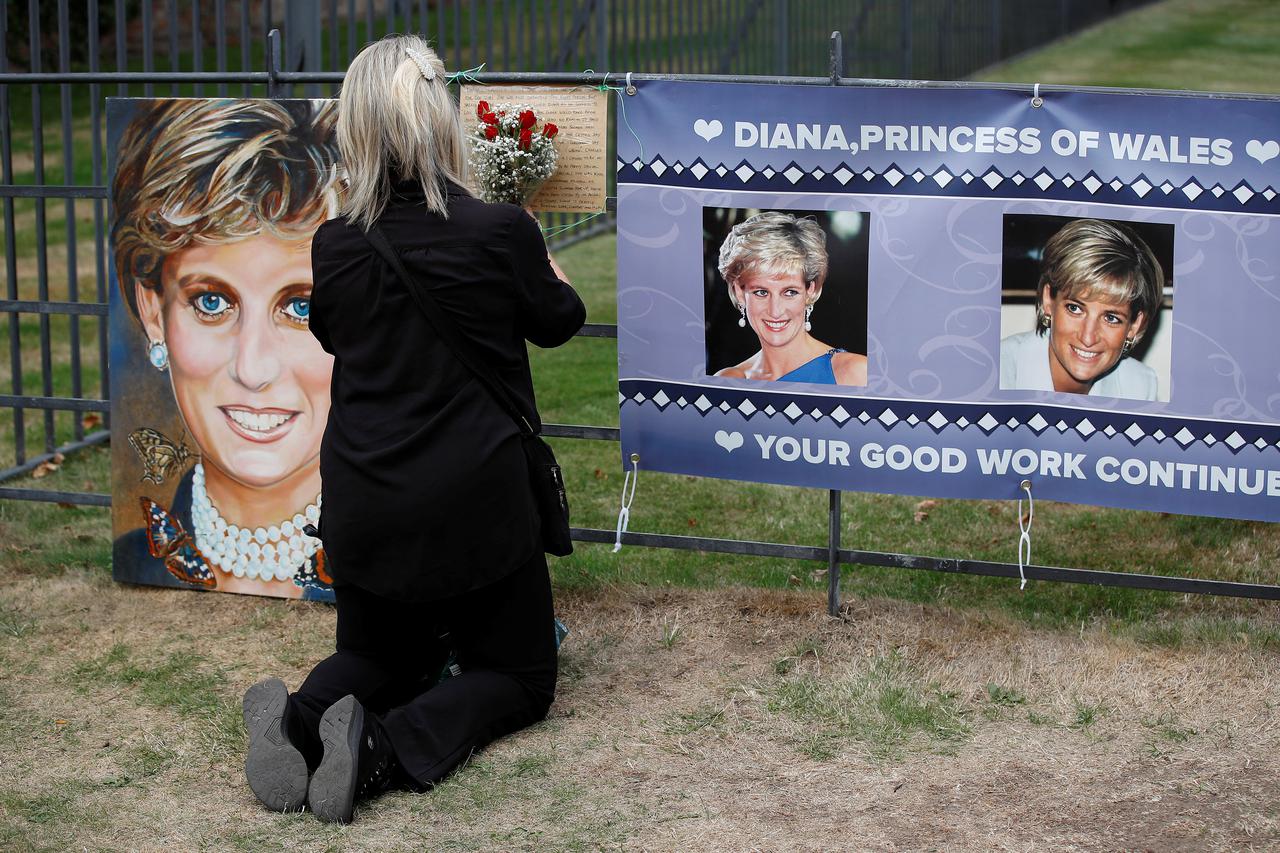 A person places flowers in a tribute to Princess Diana, on the 25th anniversary of her death, outside Kensington Palace, in London