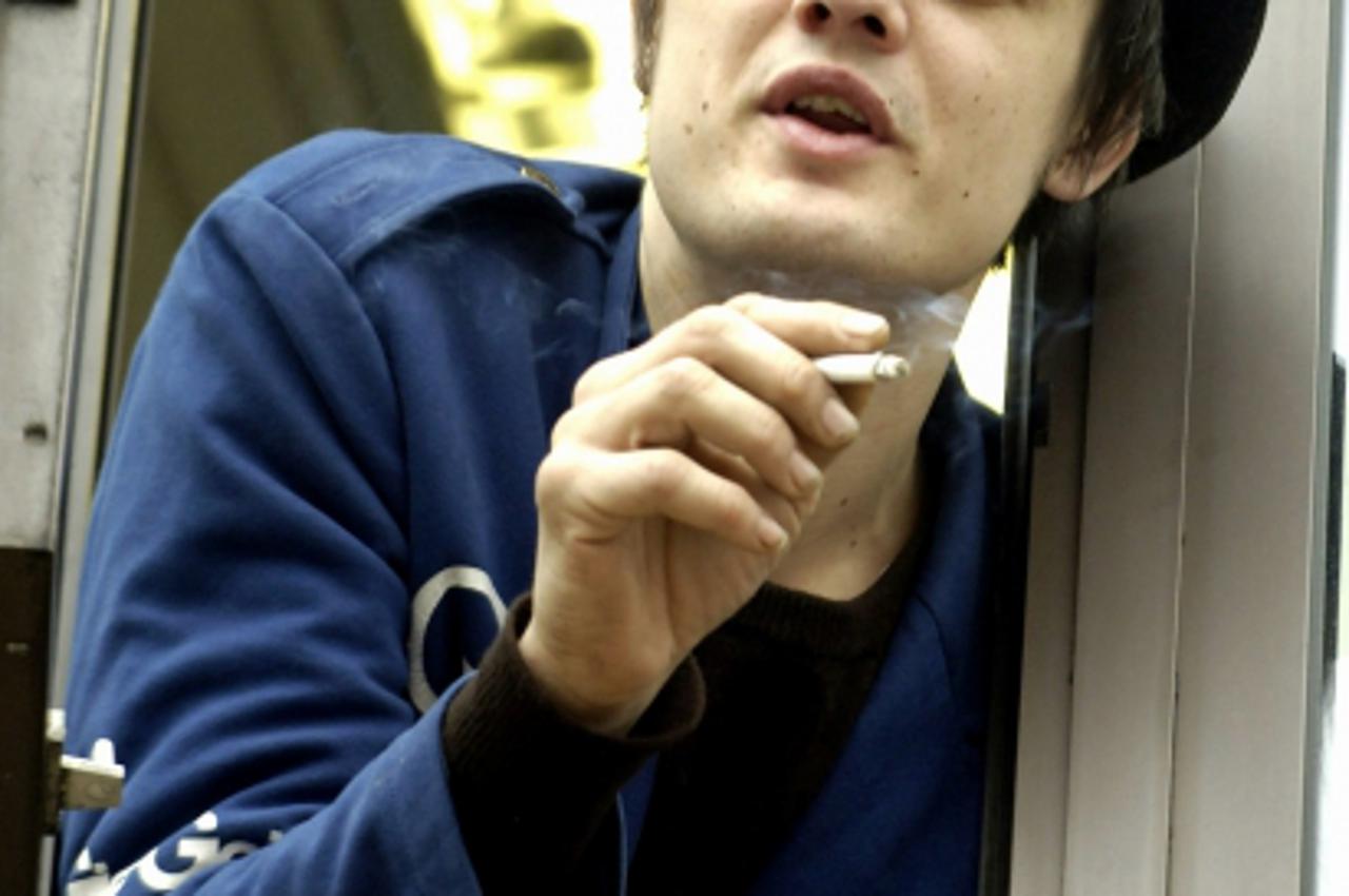 'British singer Pete Doherty leans from out of an upper floor window of Thames Magistrates Court in east London, 09 March 2006.  Doherty was back in court Thursday to face fresh charges of drugs posse