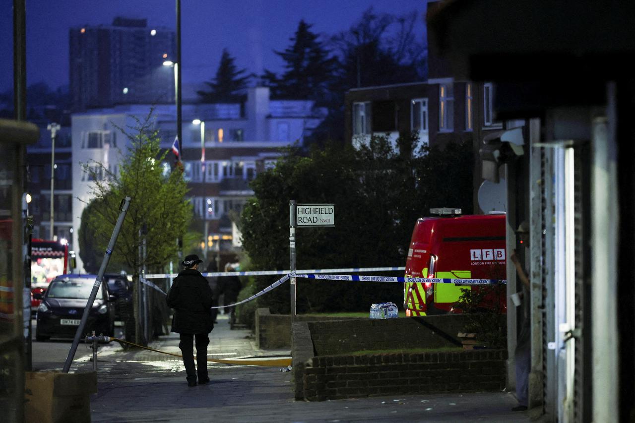 A police officer walks next to a police cordon line near the scene after four ambulances belonging to Hatzola, a Jewish community organisation, were set on fire in northwest London