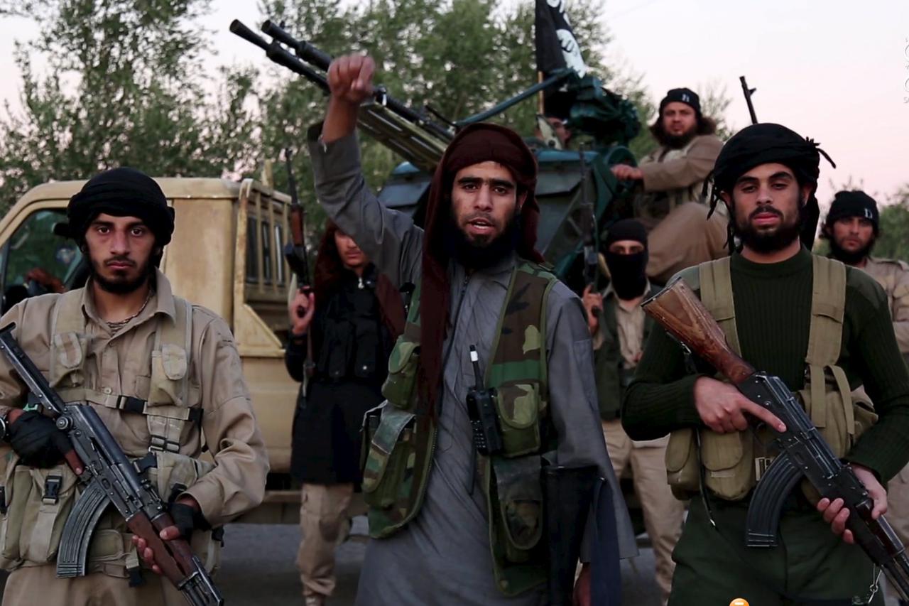 A man (C) identified in the subtitiles as Al Karar the Iraqi gestures as he speaks at an undisclosed location in this image taken from undated video footage released by Islamic State. Islamic State warned in the new video on November 16, 2015 that countri