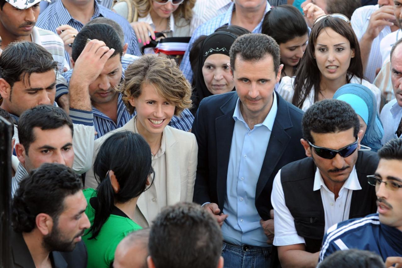 'Syrian President Bashar al-Assad (C-R) and First Lady Asma al-Assad (C-L) arrive at Al-Jalaa Stadium in Damascus on June 30, 2011 to meet with regime supporters who made the biggest Syrian flag as a 