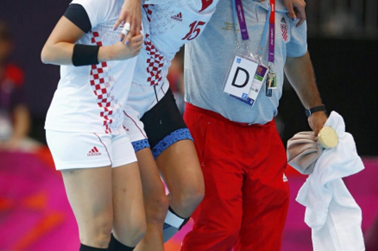 'Croatia\'s Andrea Penezic (C) is assisted out of the court after an injury in their women\'s handball quarterfinals match against Spain at the Copper Box venue during the London 2012 Olympic Games Au