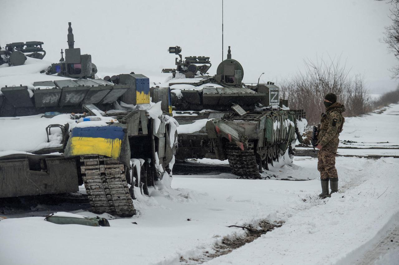 Ukrainian serviceman stands near captured Russian tanks in the north of the Kharkiv region