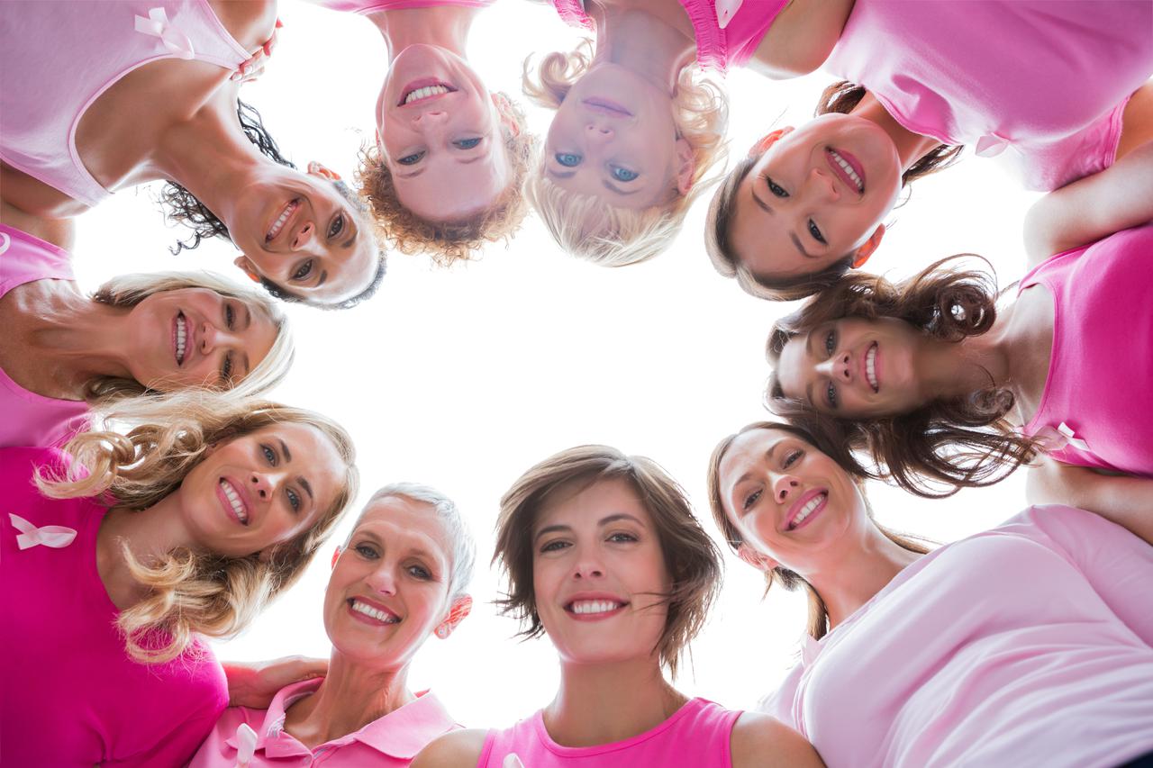 Group of happy women in circle wearing pink for breast cancer on white background