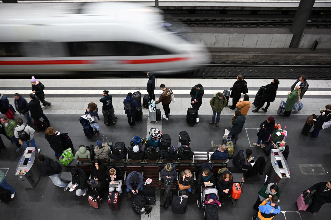 People stand on a platform with their luggage as a train arrives at the main train station, as the annual festive Christmas holidays near in Berlin