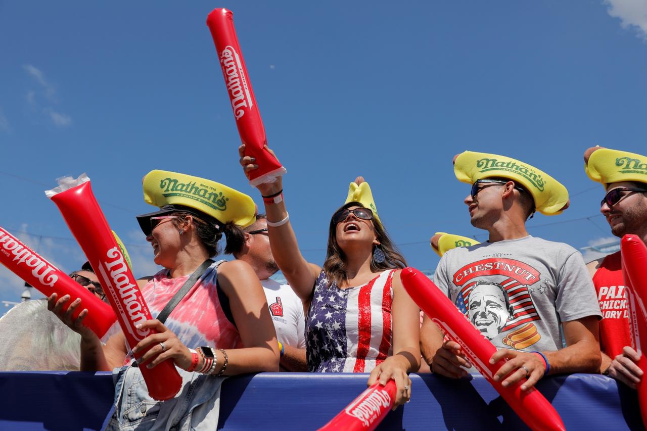 People cheer ahead of the Nathan's Famous Fourth of July Hot Dog-Eating Contest held on Independence Day at Maimonides Park in Brooklyn, New York City