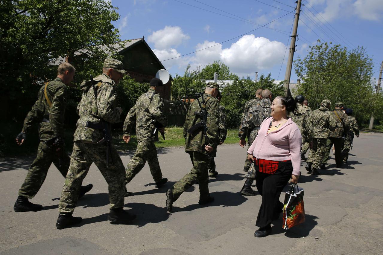 A local woman welcomes armed pro-Russia militia men marching towards a polling station during a referendum in the eastern Ukrainian city of Slaviansk May 11, 2014. Rebels pressed ahead with a referendum on self-rule in east Ukraine on Sunday and fighting 