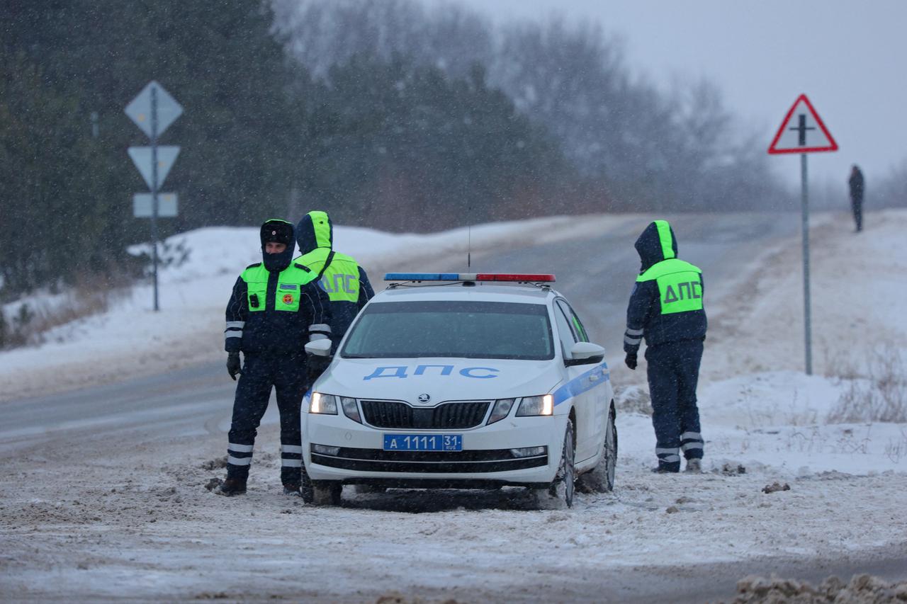 Traffic police officers stand guard on a road near the crash site of the Russian Ilyushin Il-76 military transport plane in Belgorod Region