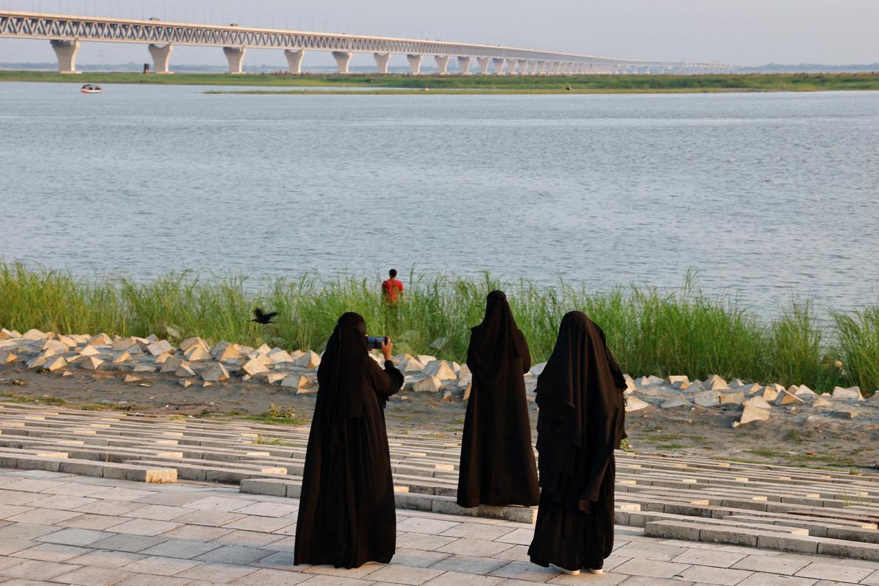 Women wearing burka take pictures on the bank of Padma River in the afternoon in Munshiganj