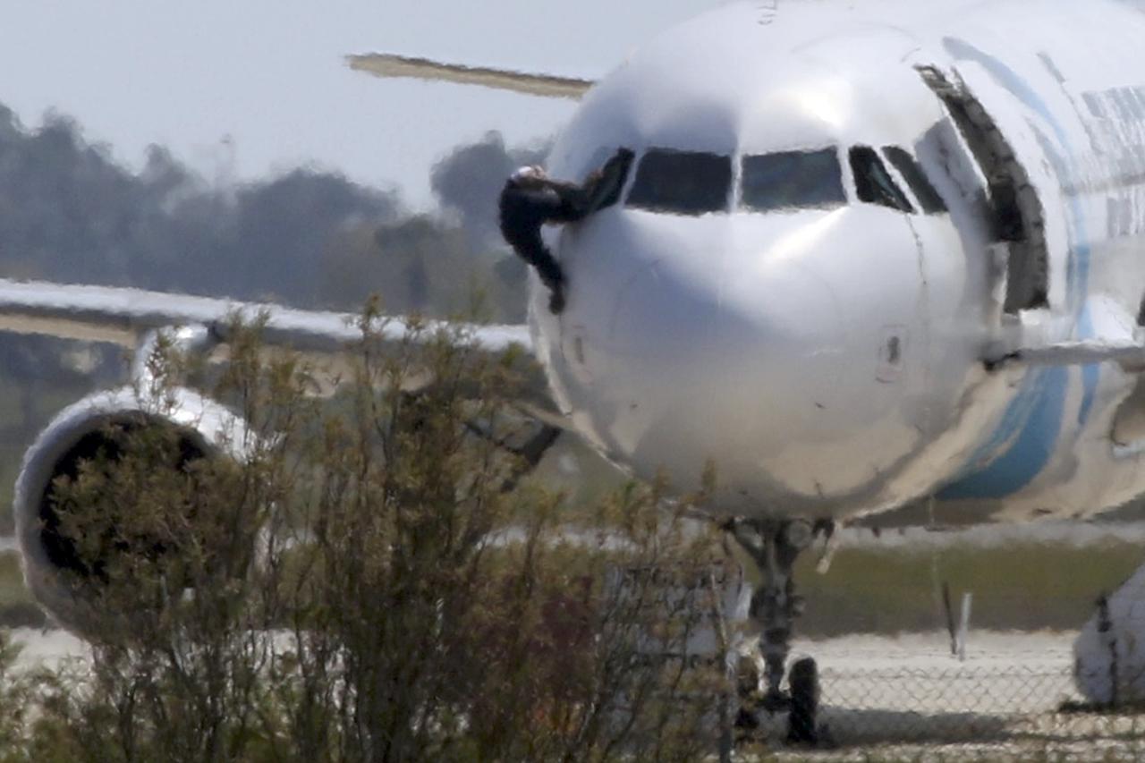 A man climbs out of the cockpit window of  the hijacked Egyptair Airbus A320 at Larnaca Airport in Larnaca, Cyprus, March 29, 2016     REUTERS/Yiannis Kourtoglou