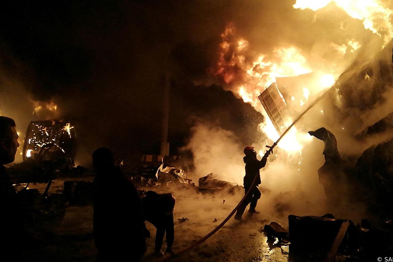 A Firefighter douses flames after Syrian state media reported an Israeli missile attack in a container storage area, at Syrian port of Latakia