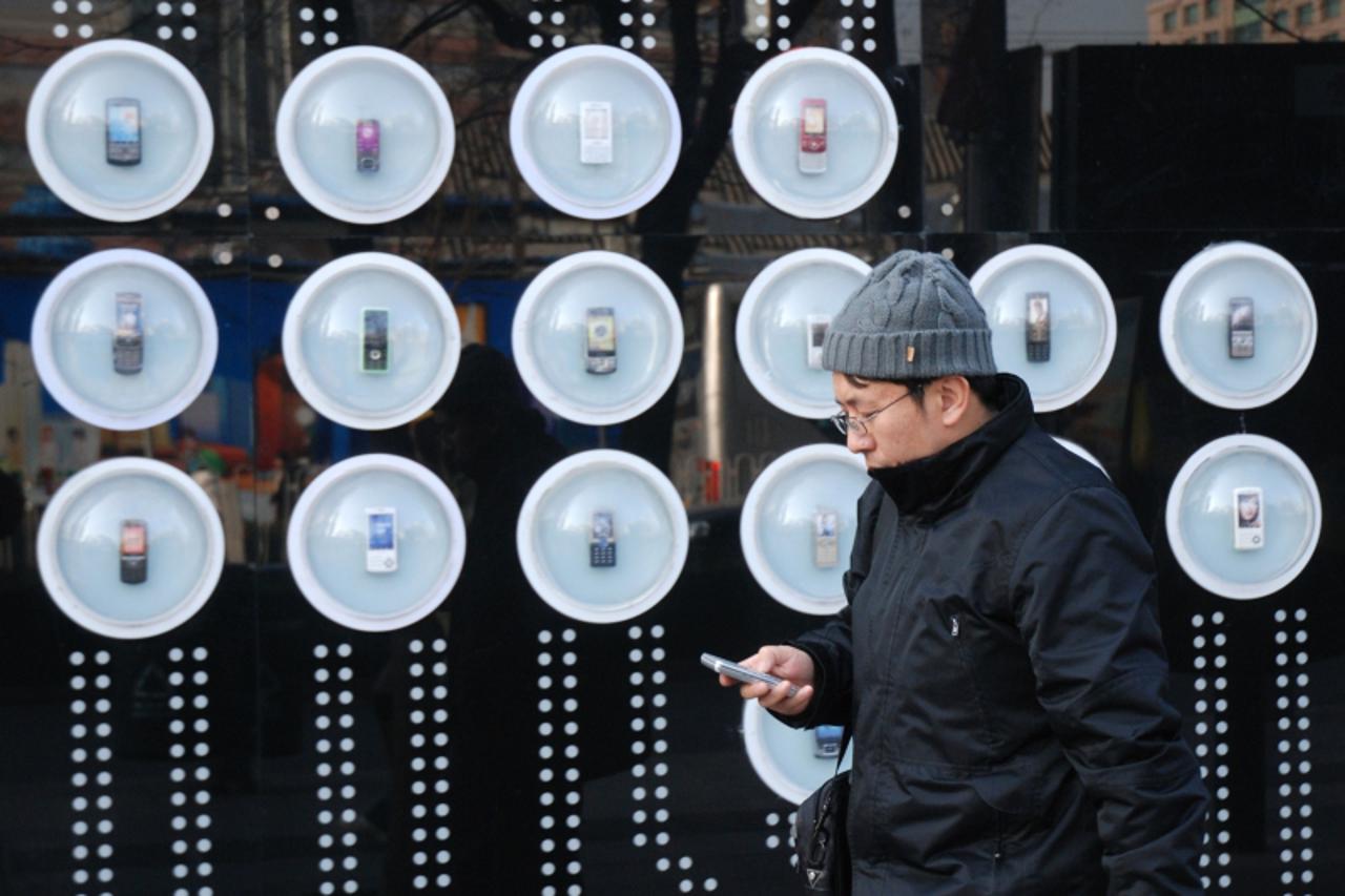 'A man walks past a mobile phone outlet in Beijing on December 8, 2009.   Research in Motion said it planned to expand the China market for its BlackBerry smartphone to include consumers and small bus