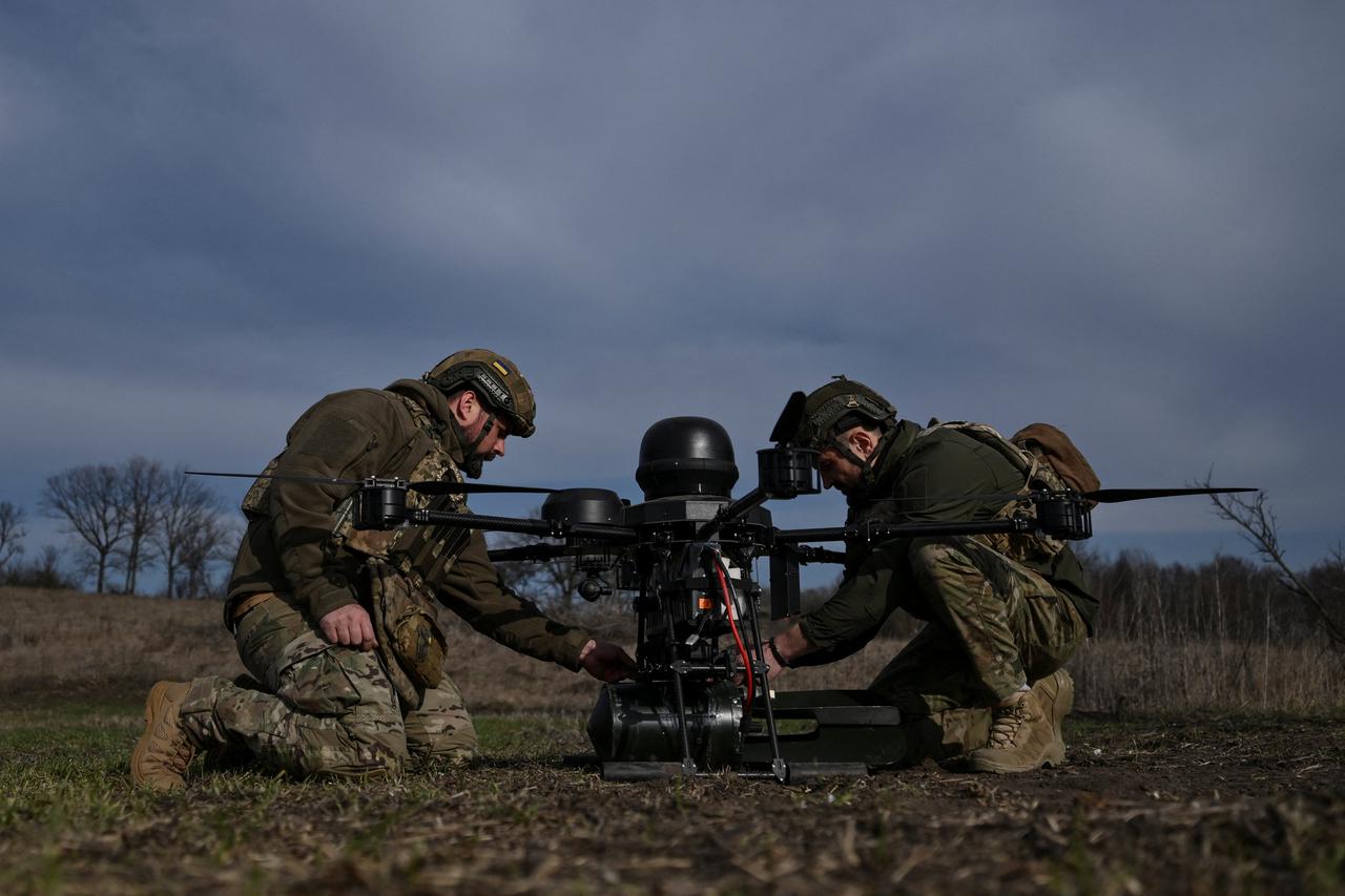 Ukrainian servicemen attach a small air bomb to a heavy strike drone before a test flight at a training ground in Zaporizhzhia region