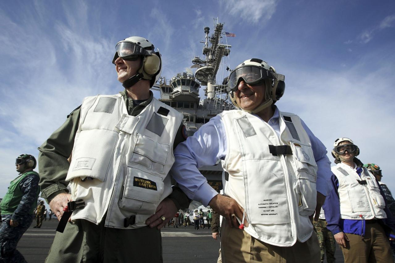 'U.S. Defense Secretary Leon Panetta (R), escorted by Commander of Strike Group Twelve Rear Admiral Walter E. Carter Jr. (L), watches day flight operations from the flight deck of the aircraft carrier