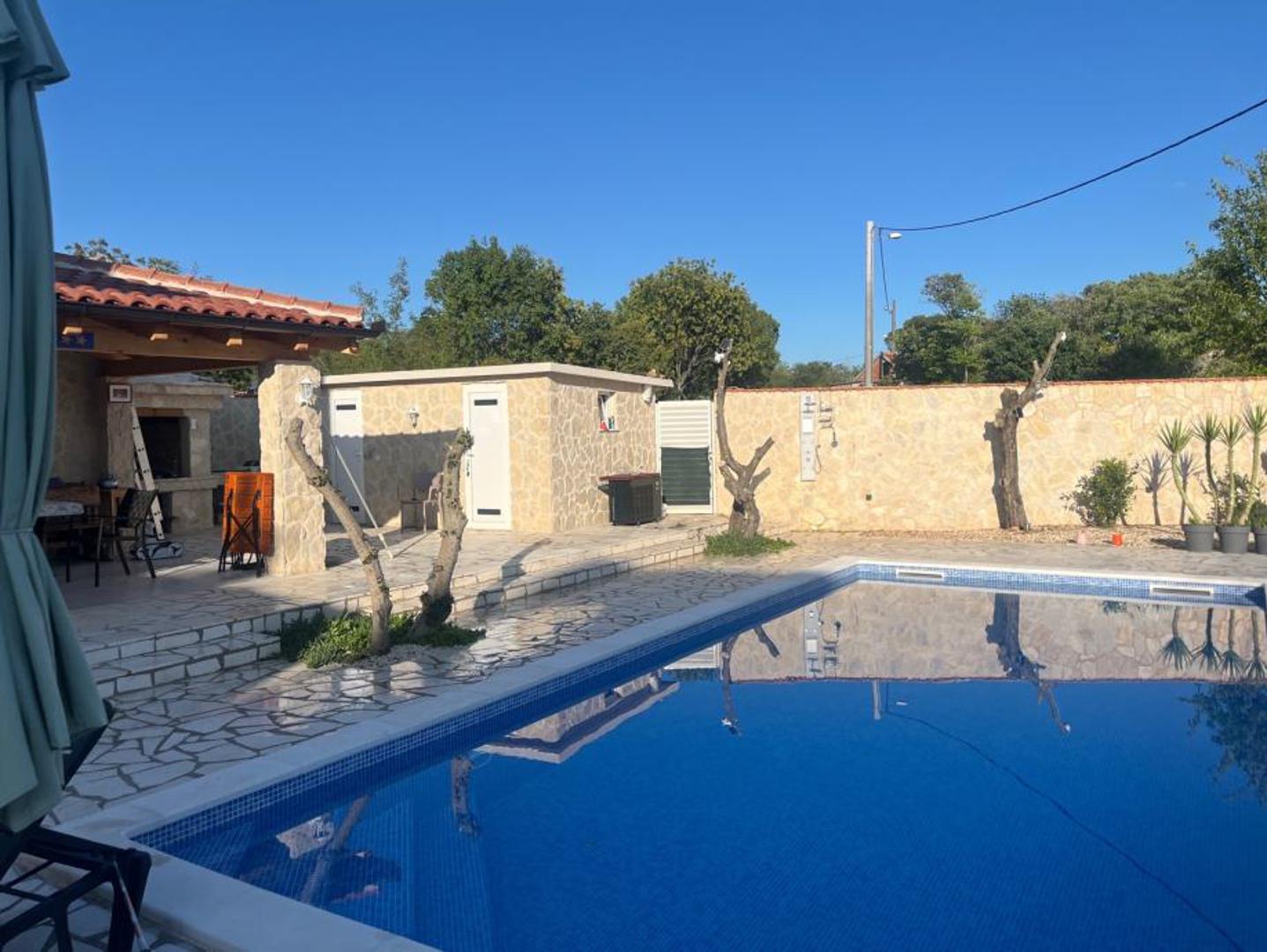 Uz to, objekt uključuje i vinski podrum, vanjski sanitarni čvor te moderan sustav video nadzora. Potpuna privatnost osigurana je uređenim graničnim zidovima i automatskom aluminijskom kliznom kapijom, a cijeli prostor oko kuće osmišljen je tako da održavanje ne zahtijeva mnogo vremena.

