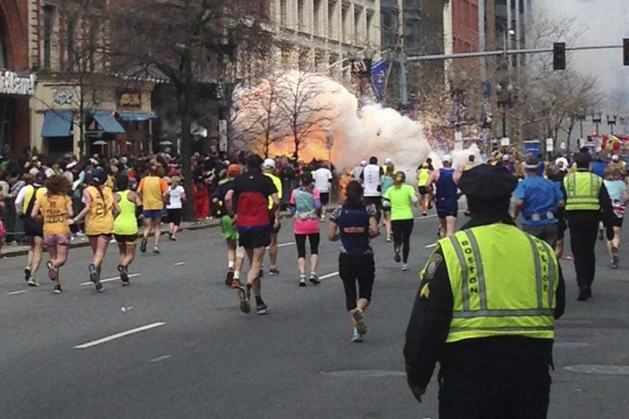 'Runners continue to run towards the finish line of the Boston Marathon as an explosion erupts near the finish line of the race in this photo exclusively licensed to Reuters by photographer Dan Lampar