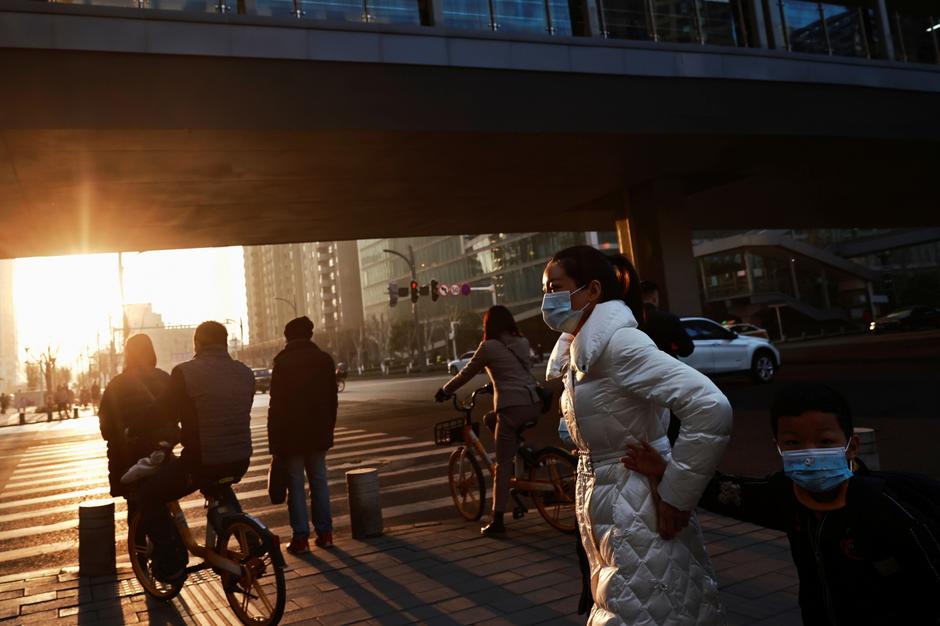 People walk along a street during morning rush hour ahead of the arrival of a World Health Organisation (WHO) team tasked with investigating the origins of the COVID-19 pandemic in Wuhan