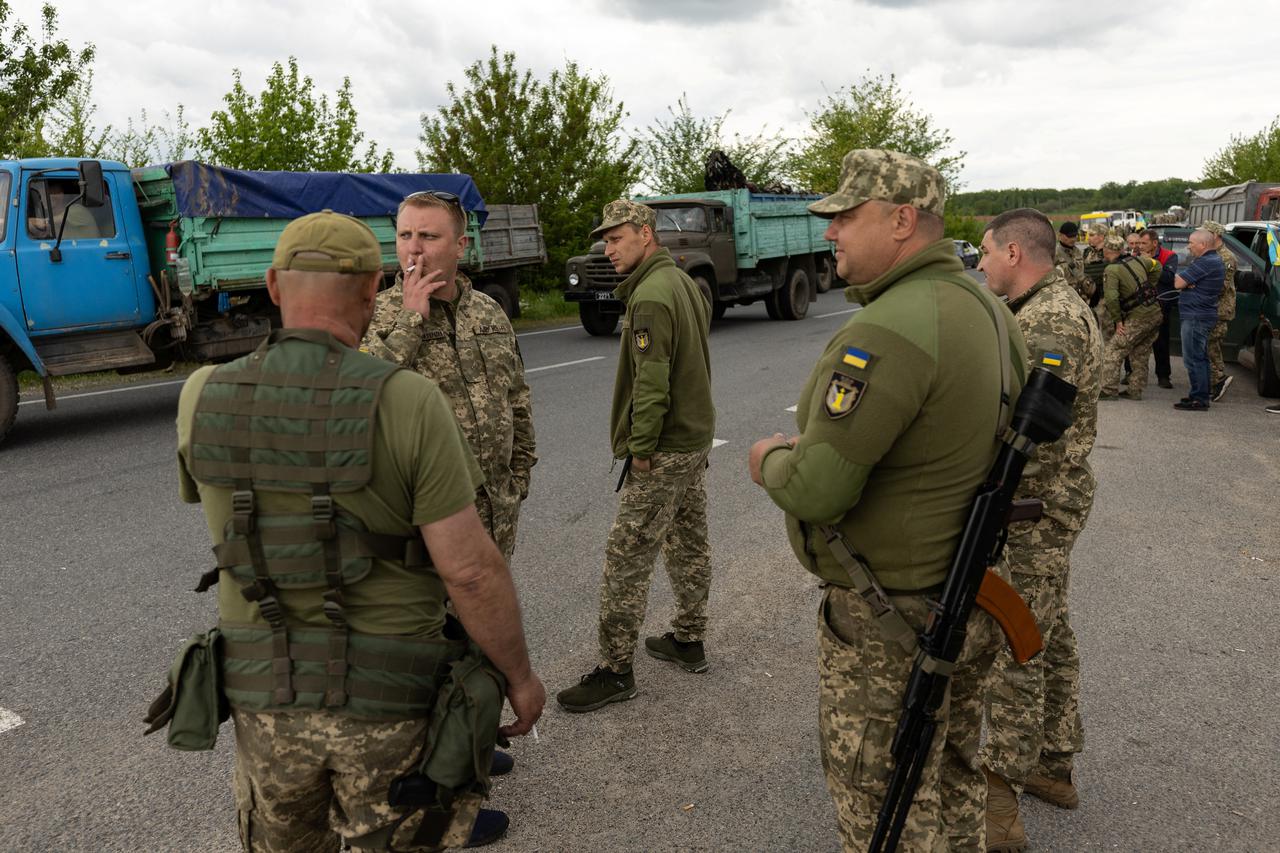 Ukrainian soldiers and volunteers from territorial defense forces pause on the road, near Oleksandriya