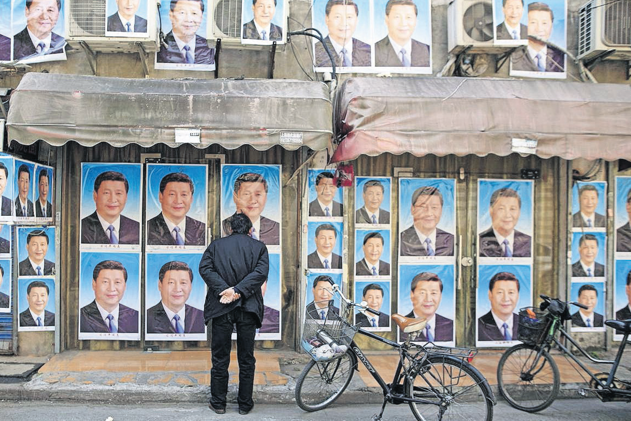 Muškarac promatra predsjednika Kine na stotinama plakata na jednoj zgradi u Šangaju