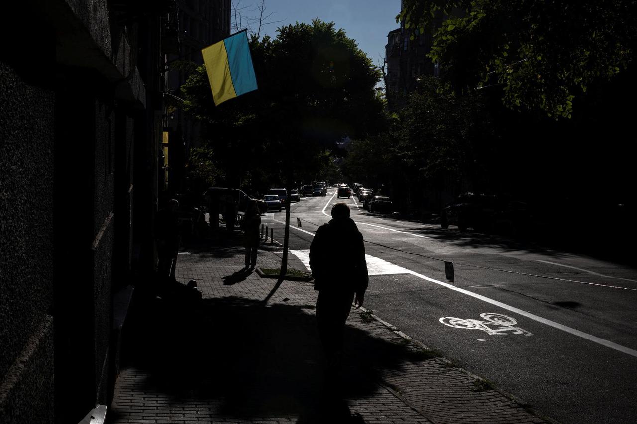 A man walks under a Ukrainian flag in a street in Kyiv