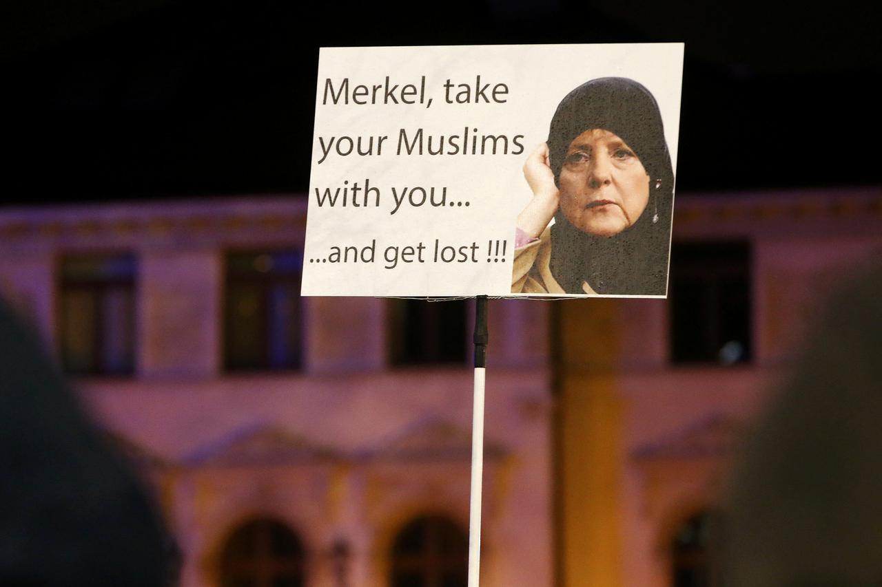 Members of LEGIDA, the Leipzig arm of the anti-Islam movement Patriotic Europeans Against the Islamisation of the West (PEGIDA), hold a poster depicting German Chancellor Angela Merkel during a rally in Leipzig, Germany January 11, 2016.     REUTERS/Fabri
