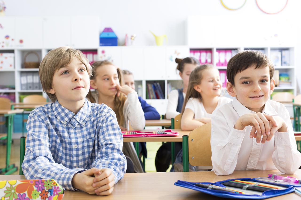Group of little happy kids at their first day at school. Sitting in pairs in school bends