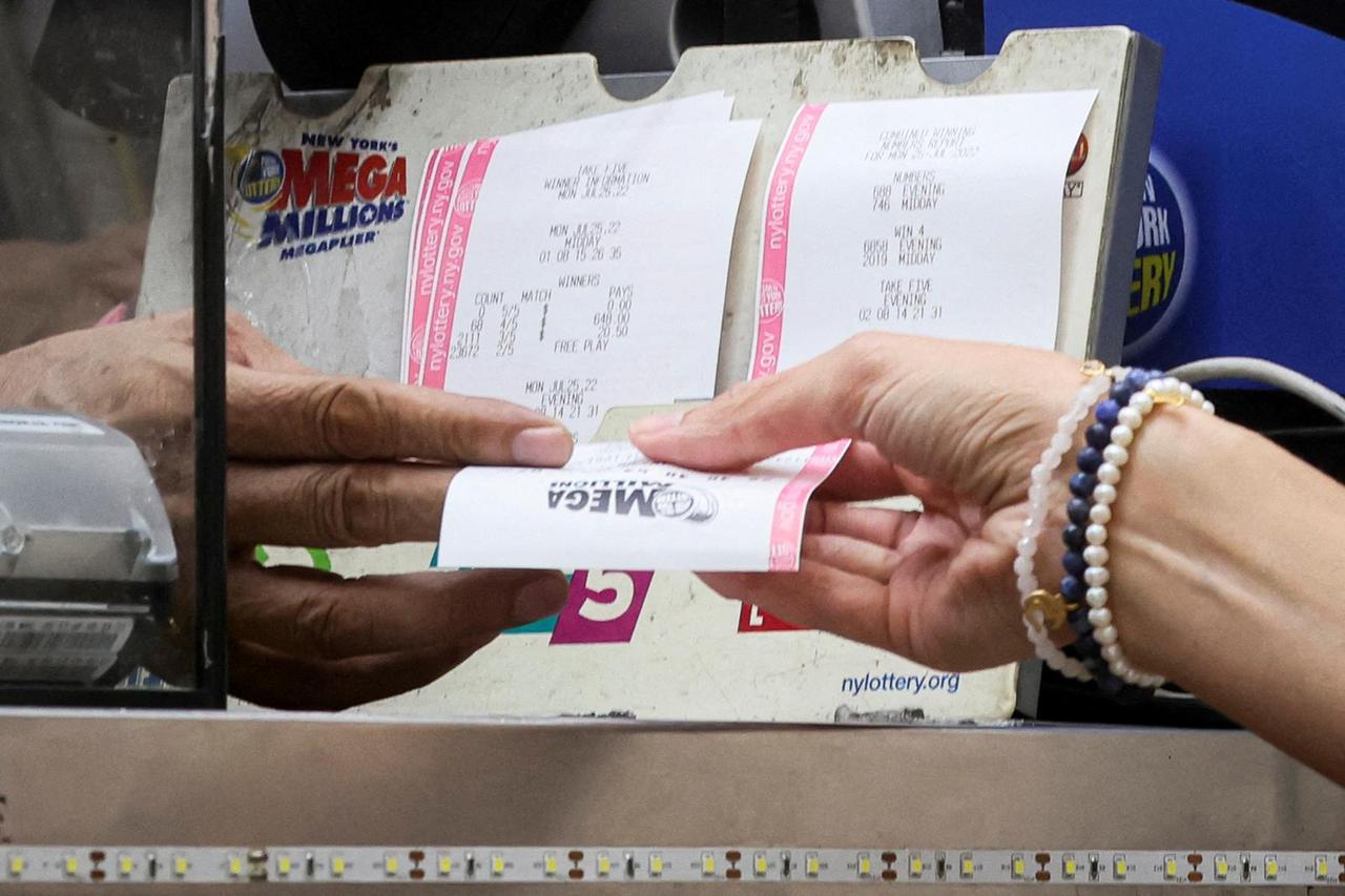 FILE PHOTO: A woman buys a ticket for the Mega Millions lottery drawing at a news stand in New York