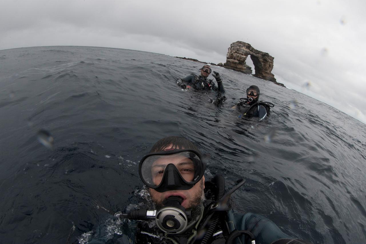 Divers pose in front of Darwin Arch in Galapagos