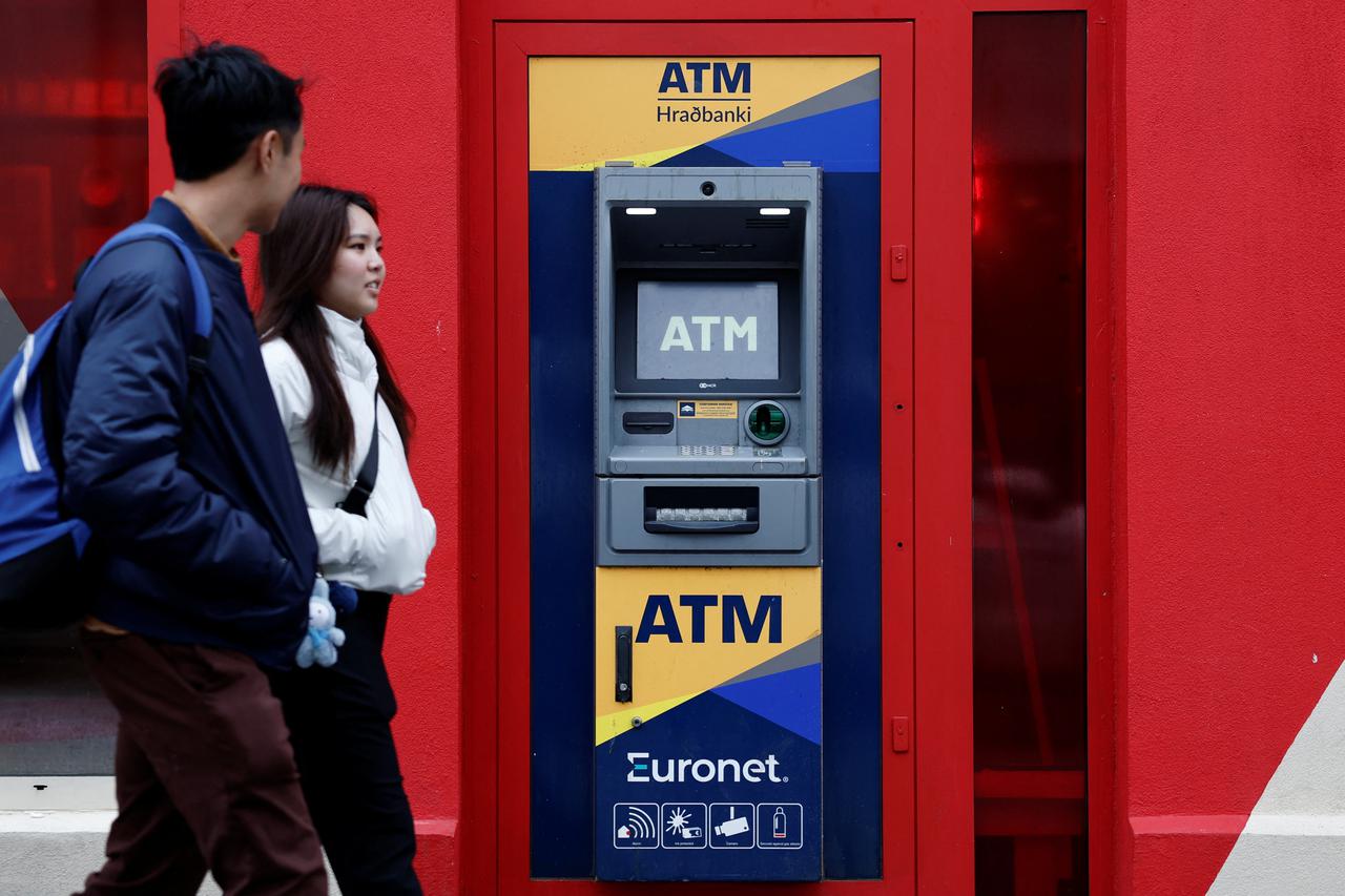 People walk near an automated teller machine (ATM) in Reykjavik