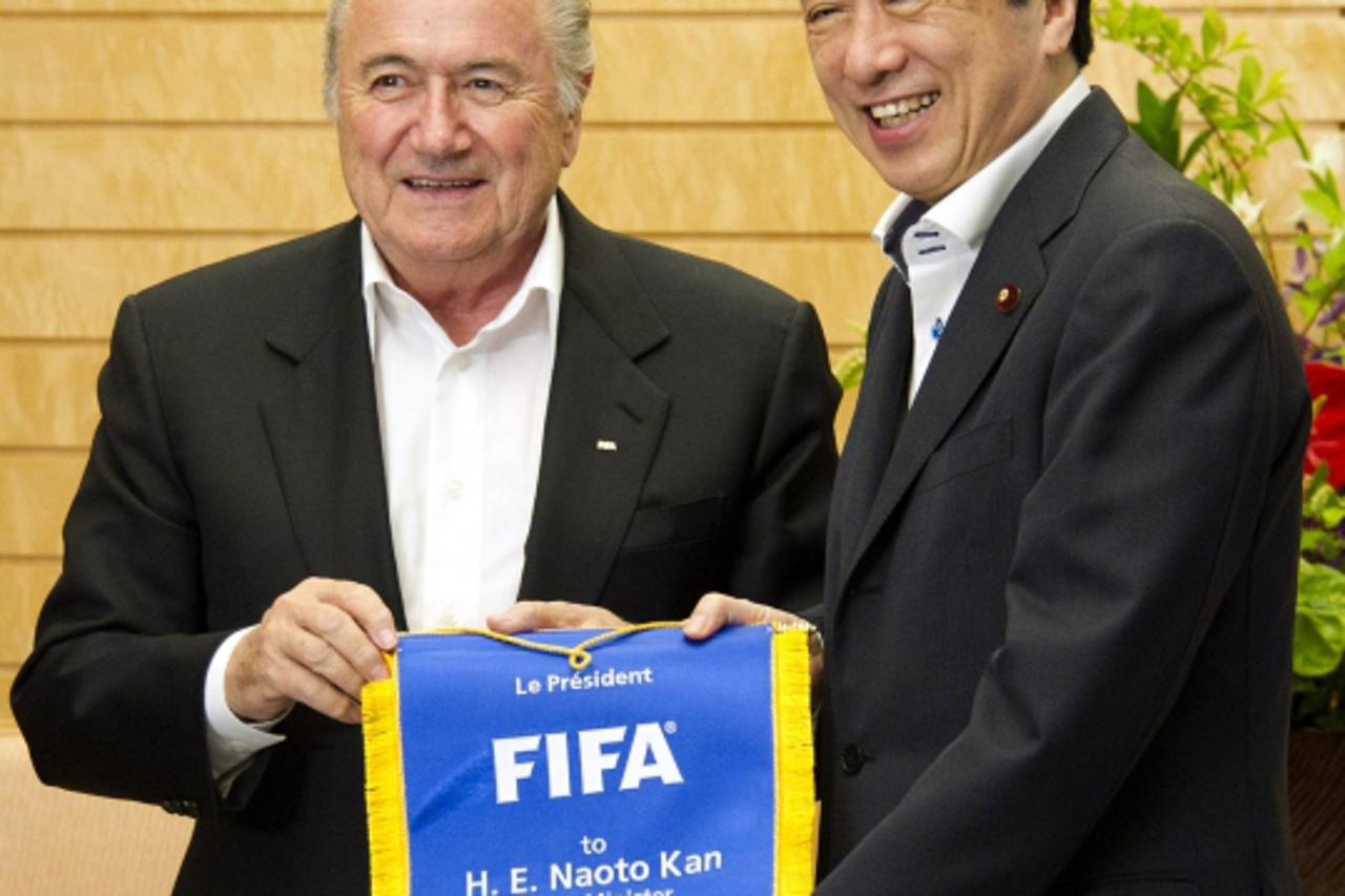 \'Japan\'s Prime Minister Naoto Kan (R) receives a complimentary FIFA banner from FIFA President Sepp Blatter prior to their talks at Kan\'s official residence in Tokyo May 23, 2011.  REUTERS/Everett 