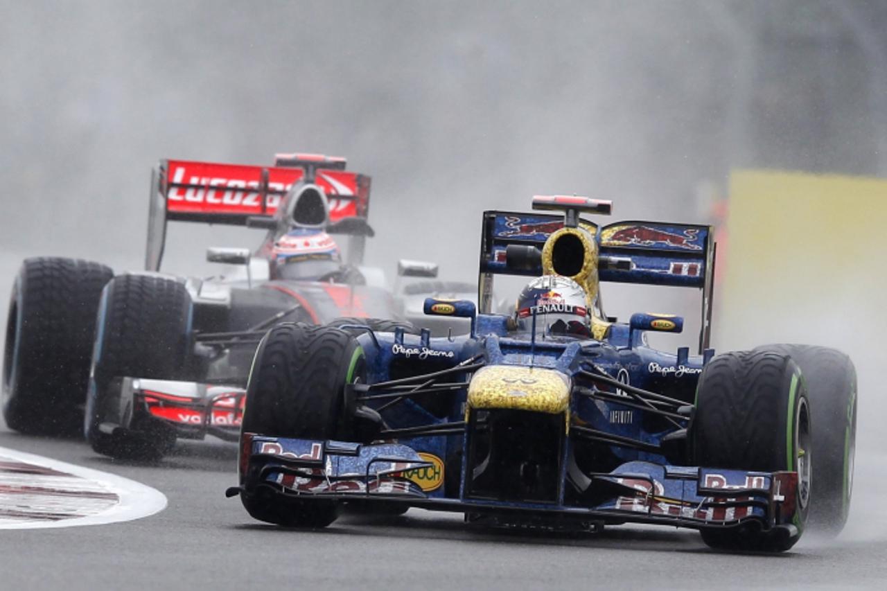 'Red Bull Formula One driver Sebastian Vettel (R) of Germany leads McLaren driver Jenson Button of Britain during the second practice session of the British Formula One Grand Prix at Silverstone, cent