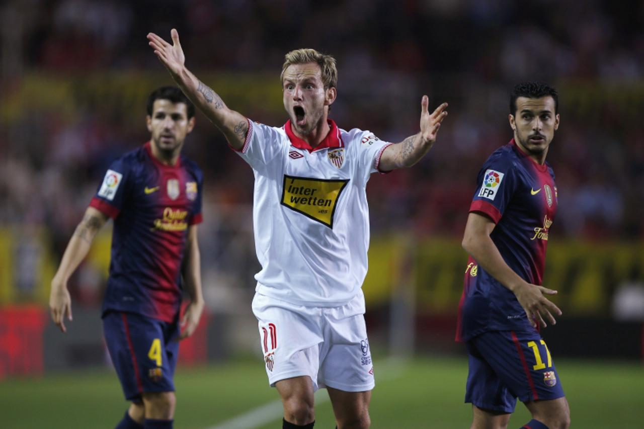 'Sevilla\'s Ivan Rakitic (C) reacts next to Barcelona\'s Cesc Fabregas (L) and Pedro Rodriguez during their Spanish First Division soccer match at Ramon Sanchez Pizjuan stadium in Seville September 29