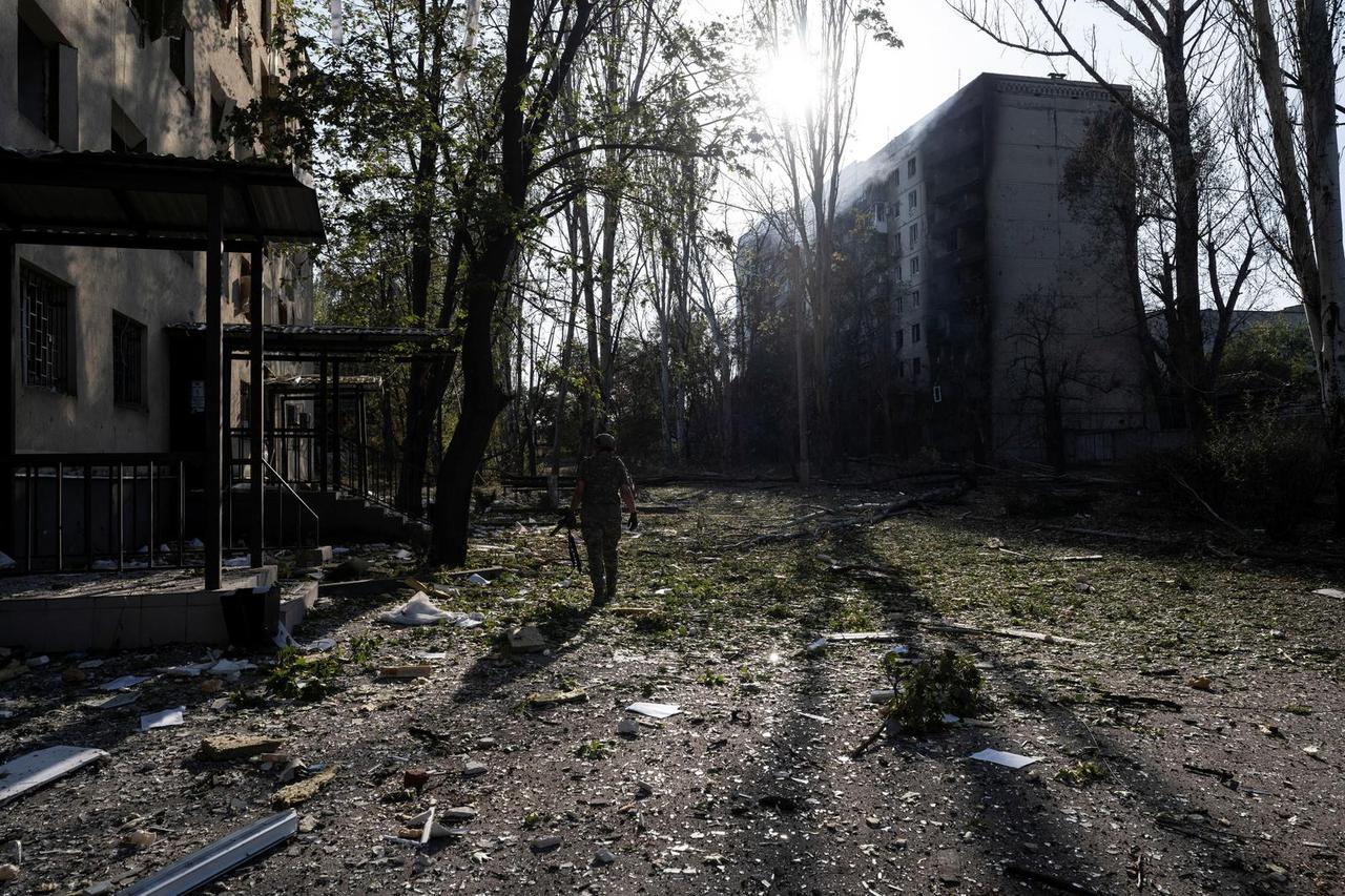 Ukrainian serviceman walks next to damaged apartment buildings in the frontline town of Kostiantynivka