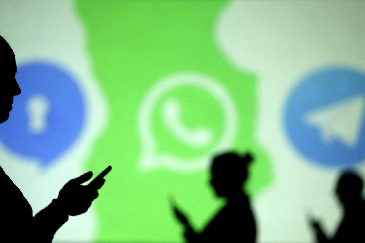 FILE PHOTO: Silhouettes of mobile users are seen next to logos of social media apps Signal, Whatsapp and Telegram projected on a screen in this picture illustration