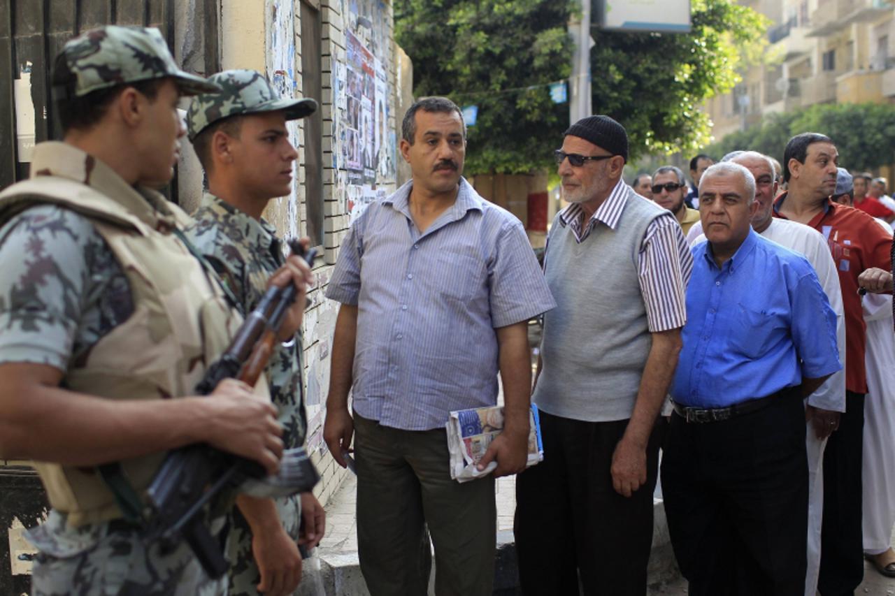 'Soldiers stand guard as voters wait outside a polling station at a school in Al-Sharqya, 60 km (37 miles) northeast of Cairo, June 16, 2012. Egypt\'s first free presidential election concludes this w