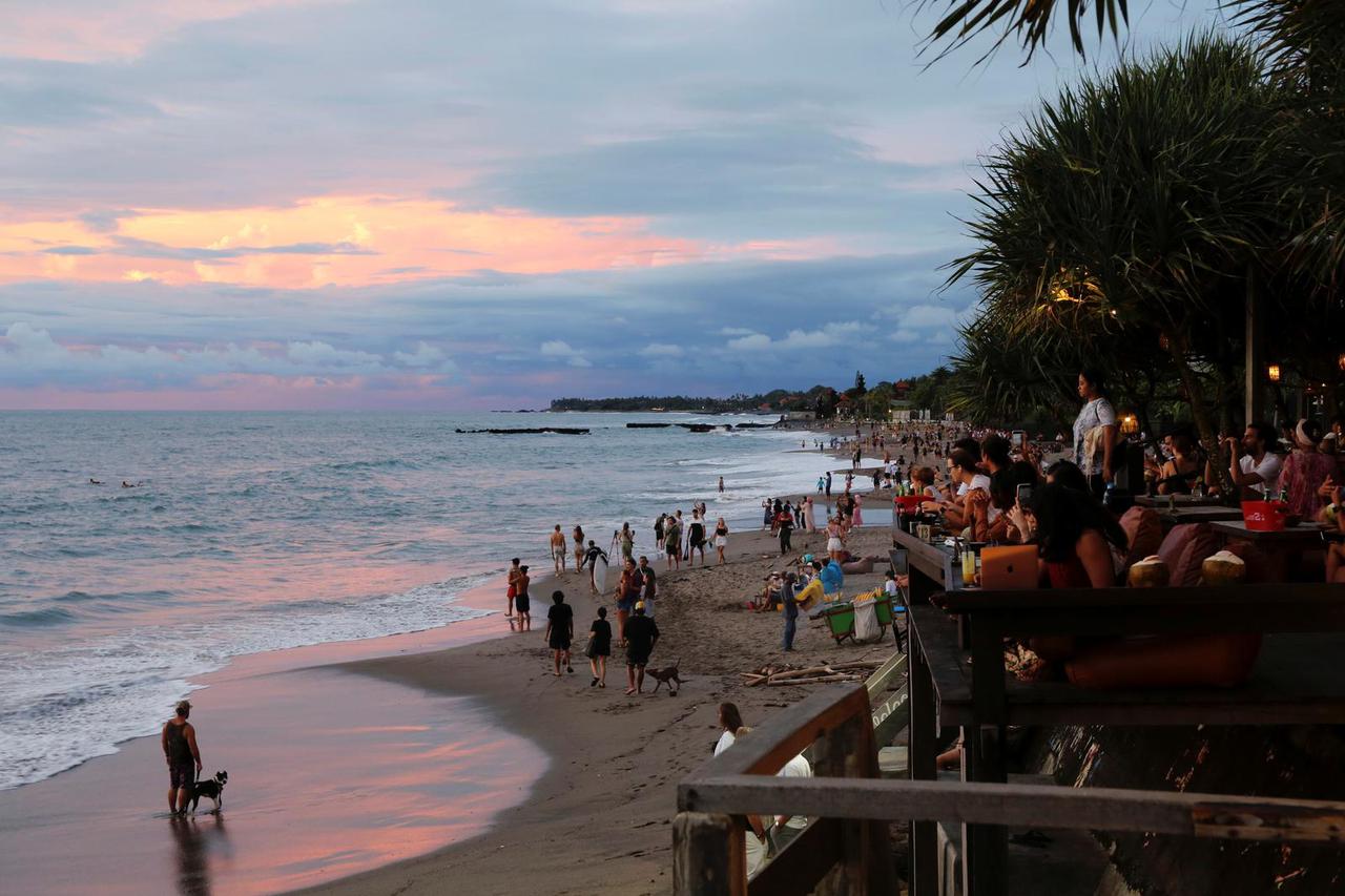 Tourists enjoy the sunset at Canggu beach amidst the COVID-19 pandemic in Bali
