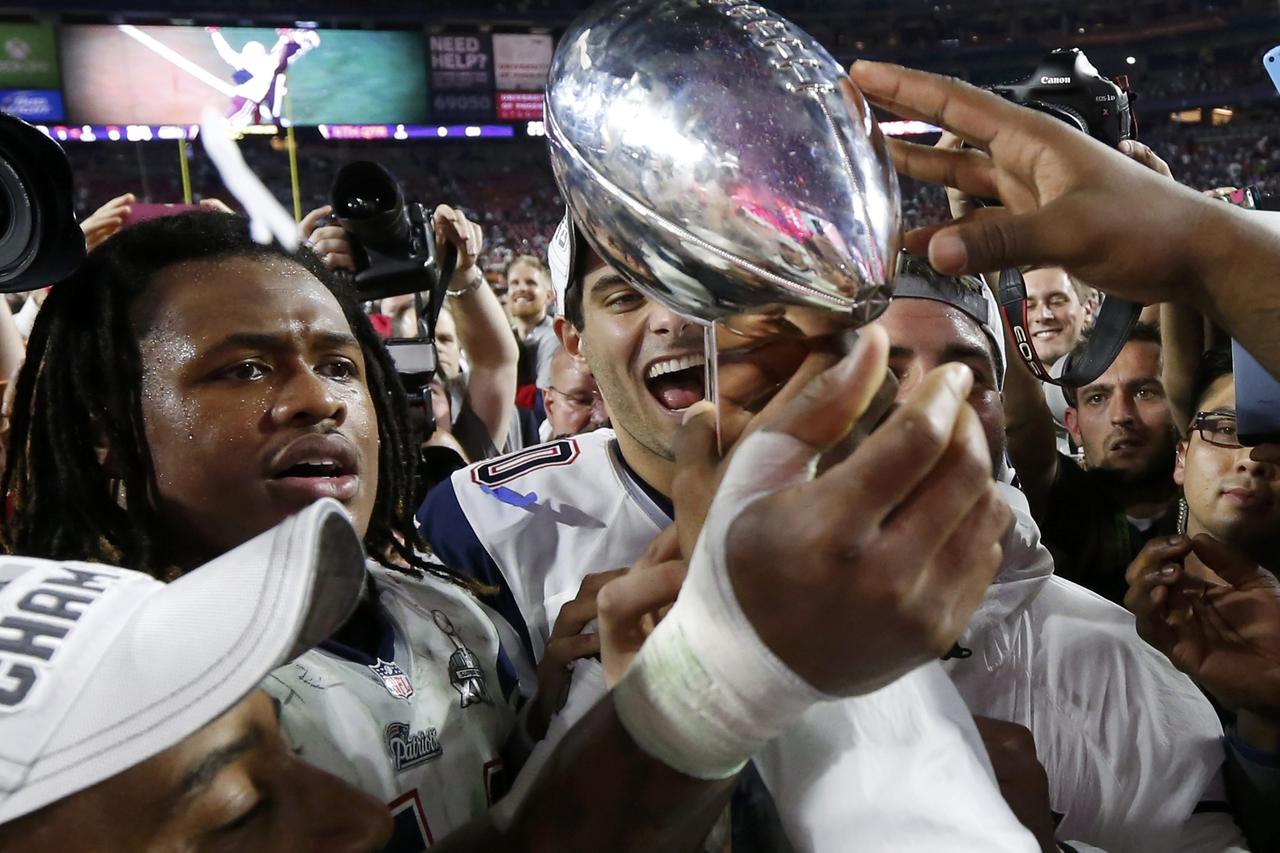 New England Patriots players reach out to touch the Vince Lombardi Trophy after they defeated the Seattle Seahawks in the NFL Super Bowl XLIX football game in Glendale, Arizona, February 1, 2015. REUTERS/Lucy Nicholson (UNITED STATES  - Tags: SPORT FOOTBA