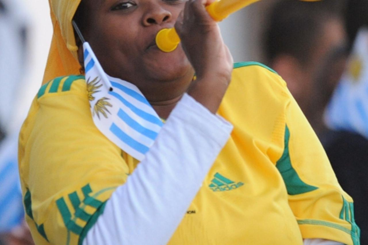'A South African woman, with an Uruguayan flag fixed in her hair, plays the vuvuzela (large coloured plastic trumpet) during a training session of Uruguay\'s football team in Kimberley on June 6, 2010