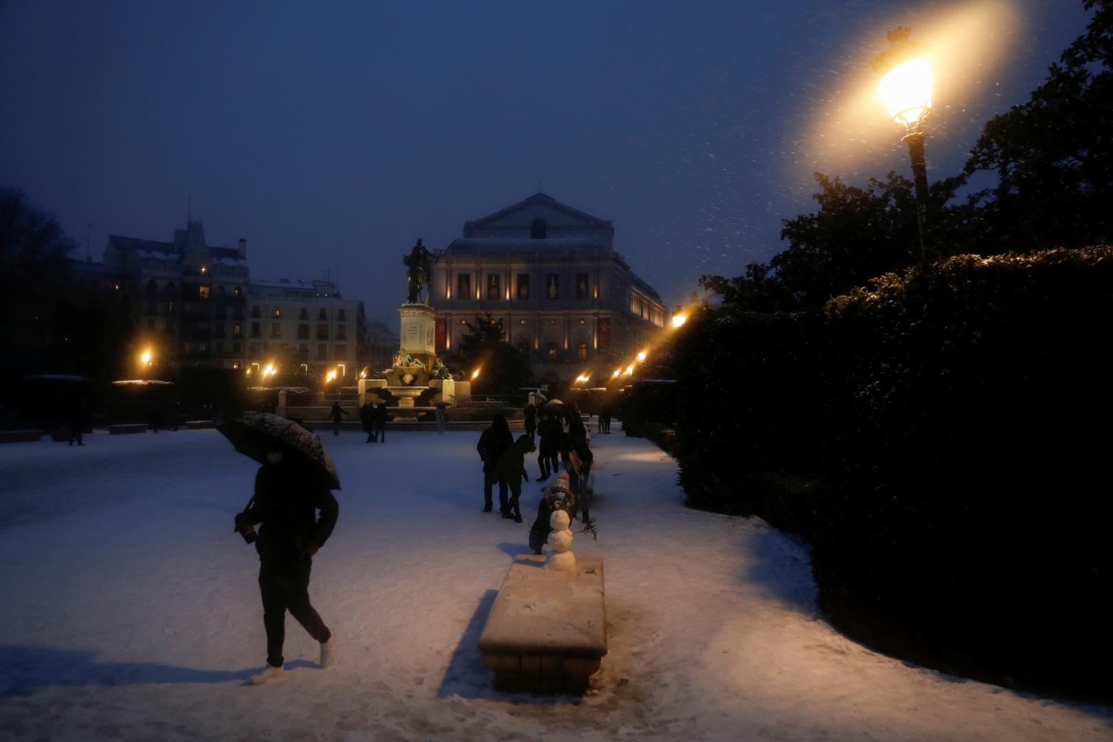 Heavy snowfall in Madrid A person walks with an umbrella next to a snowman outside the Royal Theatre during heavy snowfall in Madrid, Spain January 8, 2021. REUTERS/Susana Vera SUSANA VERA